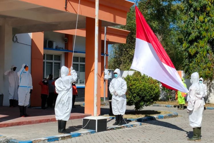 GELAR UPACARA—Petugas pemakaman jenazah covid-19 DI Kabupaten Ponorogo menggelar upacara HUT Ke-76 RI mengenakan APD lengkap di halaman Kantor BPBD Kabupaten Ponorogo, Selasa (17/8/2021).