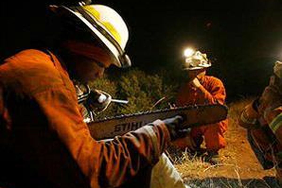 Napi anggota kru pemadam kebakaran mengasah mata gergaji mesinnya saat istirahat dari pemadaman kebakaran api di California.
