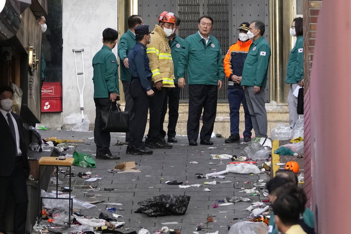 South Korean President Yoon Suk Yeol, center, is briefed at the scene where dozens of people died and were injured in Seoul, South Korea, Sunday, Oct. 30, 2022, after a mass of mostly young people celebrating Halloween festivities became trapped and crushed as the crowd surged into a narrow alley. (AP Photo/Lee Jin-man)