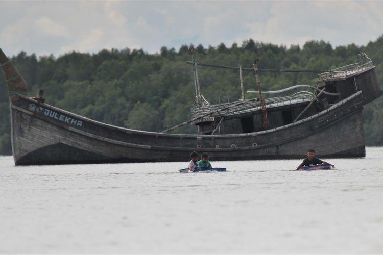 3 Bocah dari Desa Kuala Besar saat bermain perahu kecil di depan Kapal TB Julekha di perairan Desa Karang Gading, Deli Serdang,Rabu (17/1/2024)