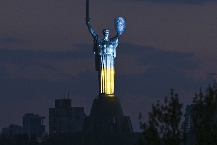 Warna bendera Ukraina menyala di patung Ibu Tanah Air saat malam peringatan Perang Dunia II di Kyiv, 8 Mei 2022.