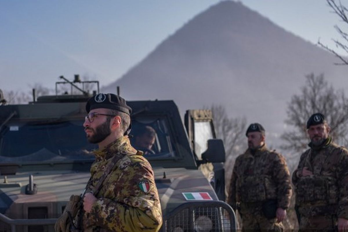 Tentara Italia yang bertugas dalam misi penjaga perdamaian internasional pimpinan NATO di Kosovo berpatroli di dekat jalan yang dibarikade dengan truk oleh orang Serbia di desa Rudare dekat kota Zvecan pada 26 Desember 2022. 