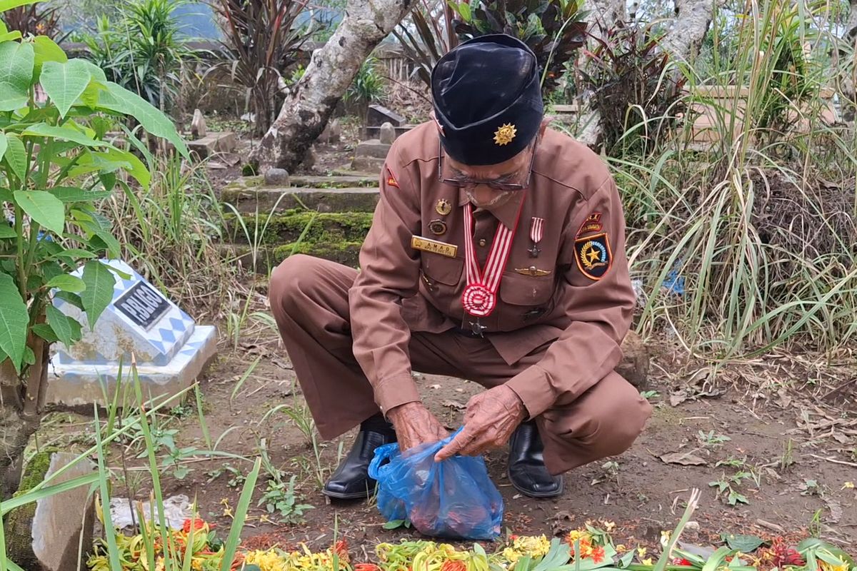 Amad menaburkan bunga di makam Supiah
