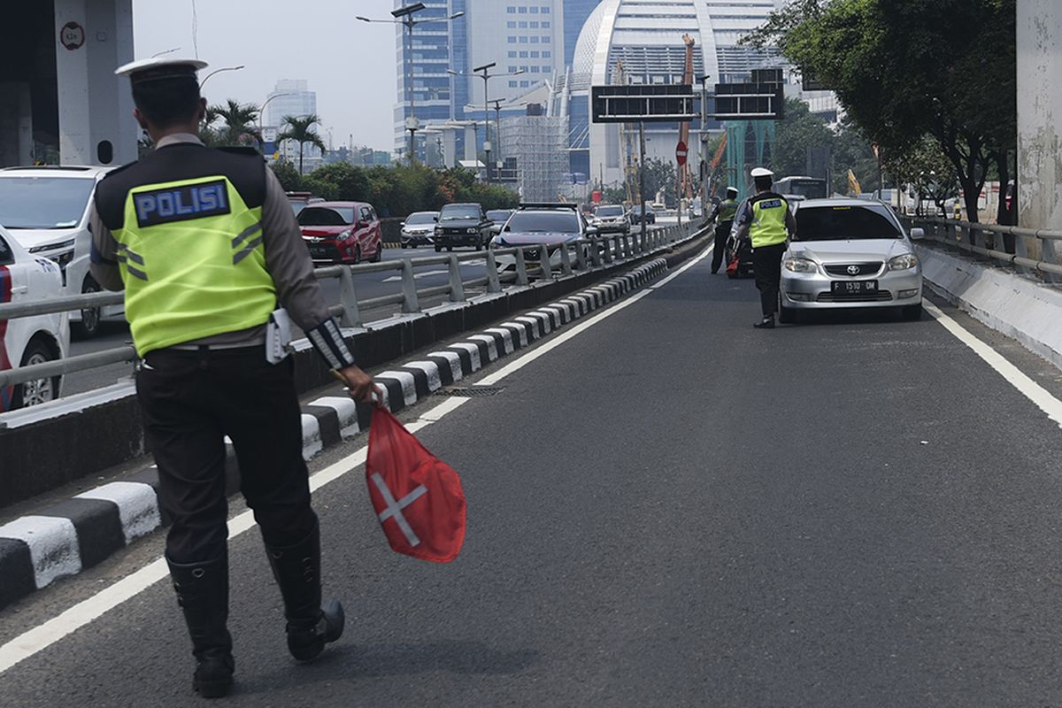 Petugas Ditlantas Polda Metro Jaya memberhentikan mobil berpelat nomor genap yang memasuki Jalan Gatot Soebroto, Jakarta, Rabu (1/8/2018). Petugas kepolisian mulai memberlakukan penindakan berupa tilang terhadap pengendara mobil yang melanggar di kawasan perluasan sistem ganjil-genap.