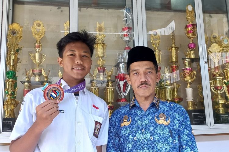 Sidiq Khoerulsyah (16), salahsatu siswa kelas XI SMAN 1 Tasikmalaya, Jawa Barat, menunjukkan medali perunggu kejuaraan dunia Taekwondo di Korea Selatan saat masuk ajaran baru di sekolahnya SMAN 1 Tasikmalaya, Senin (18/7/2022).