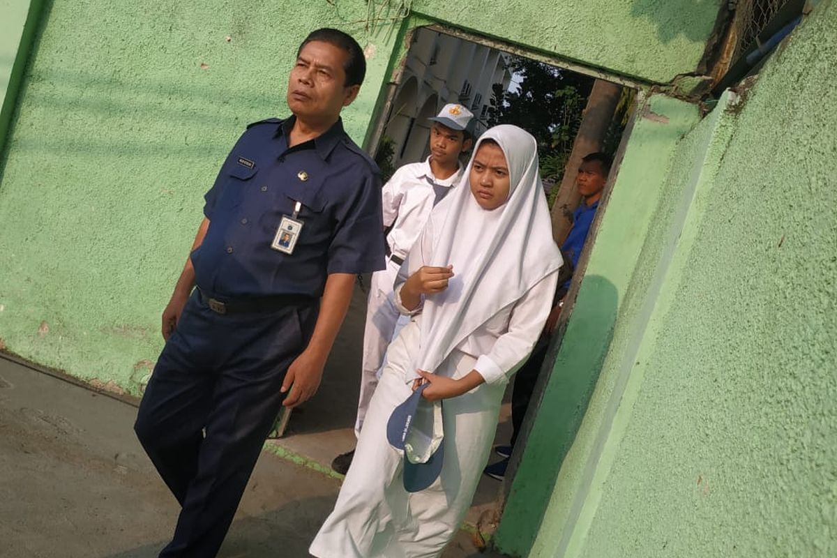 Para siswa SMKN 35 Jakarta berjalan melewati tembok yang sudah dijebol untuk mengikuti upacara pada Senin (4/11/2019)