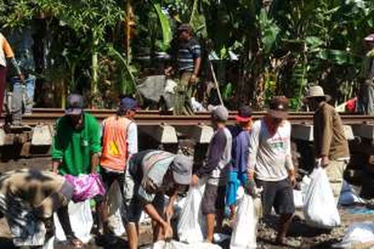 Sejumlah pekerja saat memperbaiki rel kereta yang jebol akibat banjir di Desa Tambakrejo, Kecamatan Kraton, Kabupaten Pasuruan, Jawa Timur, Jumat (1/7/2016)