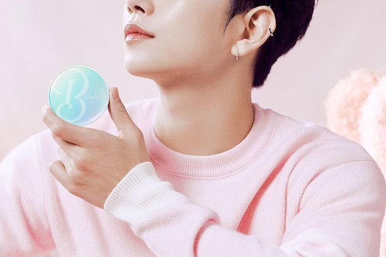 Joshua Hong mengenakan sweater pink pastel.