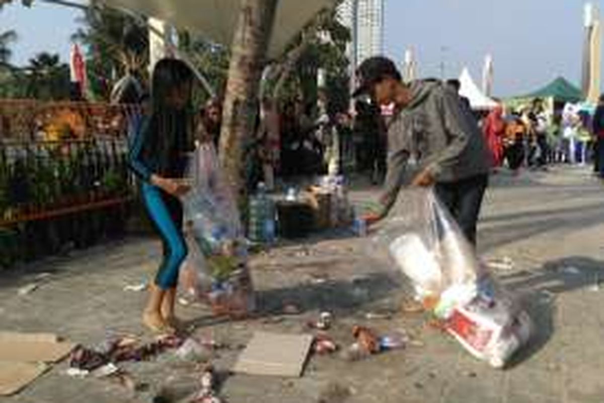 Pengunjung Ancol membersihkan sampah sisa perayaan tahun baru, Minggu (1/1/2017).
