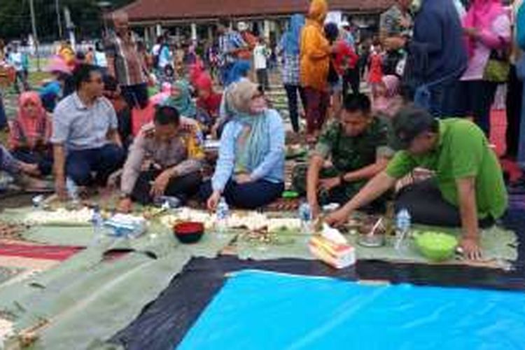 Bupati Pandeglang Irna Narulita (tengah) didampingi Kepala Kepolisian Resor Pandeglang Ajun Komisaris Besar Ary Satriyan, Komandan Kodim 0601/Pandeglang Letnan Kolonel Inf Ganiahardi, dan Ketua DPRD Pandeglang Gunawan menikmati hidangan di atas daun pisang di Alun-alun Pandeglang, Banten, Sabtu (31/12). Mereka bersama ratusan warga Pandeglang melakukan tradisi khas Pandeglang, yakni papahare atau membawa makanan untuk ditukar dan disantap bersama-sama.