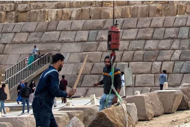 Para pekerja sedang mengangkat granit untuk melapisi permukaan piramida Menkaure di Gaza, Mesir. 