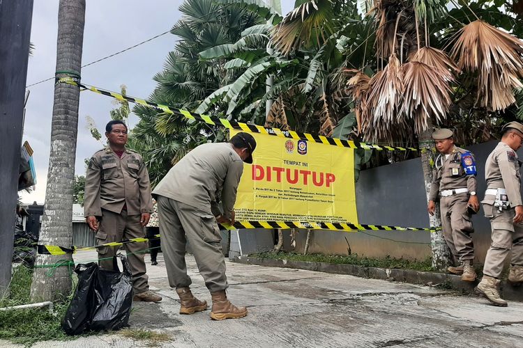 Petugas Satpol PP DI Yogyakarta (DIY) saat menutup bangunan di atas tanah kas desa berupa Kost Ekslusif Jogja Amazon Green 2 di Kalurahan Condongcatur, Kapanewon Depok, Kabupaten Sleman. Bangunan tersebut ditutup karena menggunakan tanah kas desa tanpa izin.