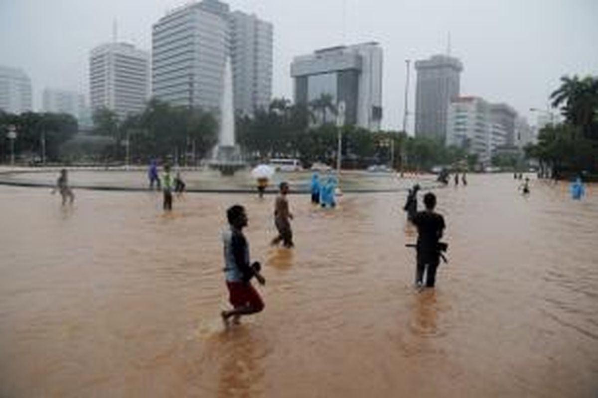 Pejalan kaki melintasi banjir di kawasan bundaran air mancur jalan MH Thamrin, Jakarta, Senin (9/2/2015). Curah hujan yang tinggi mengakibatkan sejumlah tempat di ibu kota terendam banjir. KOMPAS / LASTI KURNIA