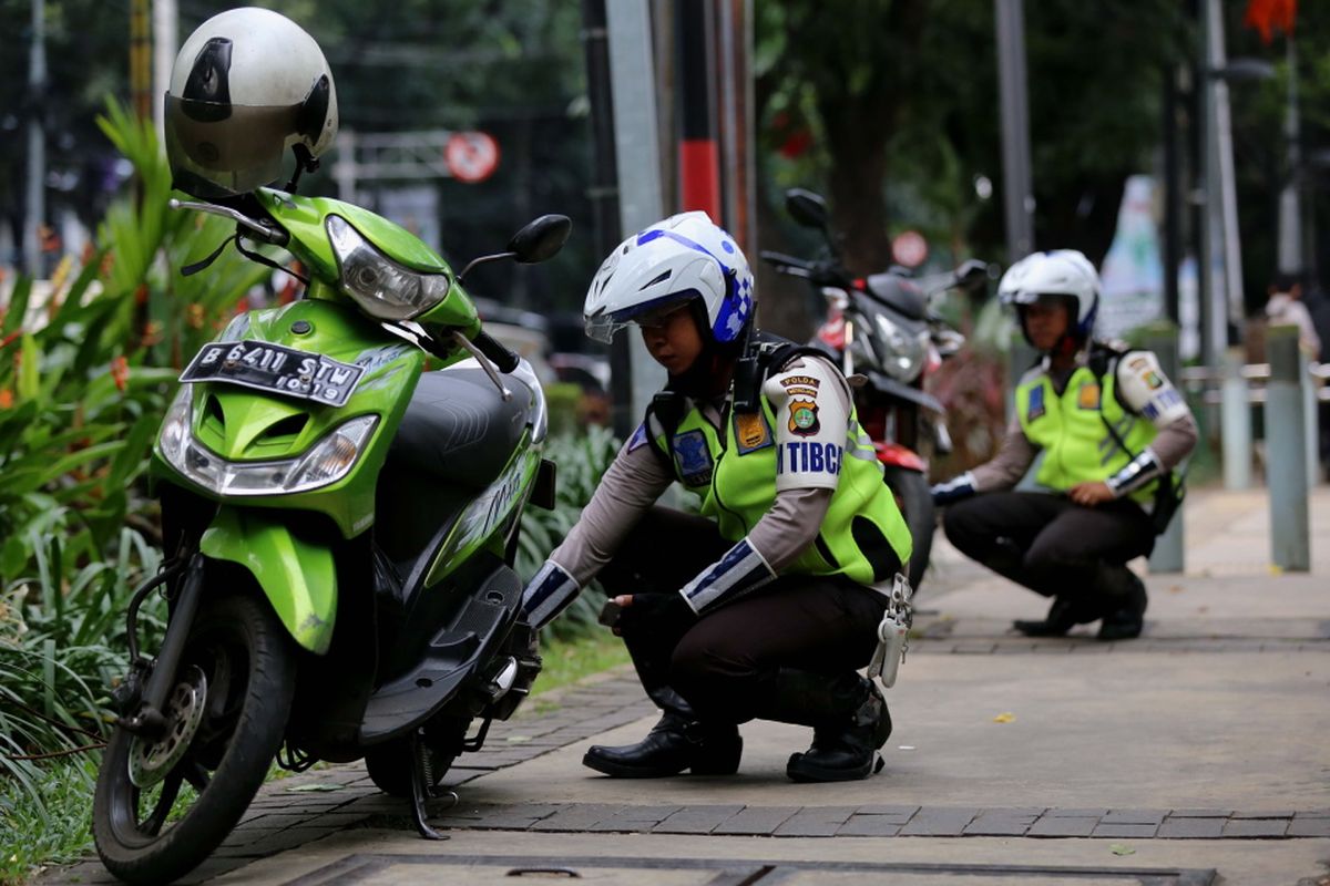 Polisi menggembosi ban sepeda motor yang parkir sembarangan di Jalan Kebon Sirih, Jakarta Pusat, Senin (17/7/2017). Pengendara sering memanfaatkan trotoar untuk memotong jalan agar bisa lebih cepat ketimbang melewati jalan raya.