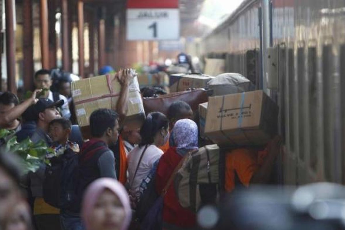 Pemudik masuk ke dalam kereta api di Stasiun Pasar Senen, Jakarta, Senin (13/7/2015).  