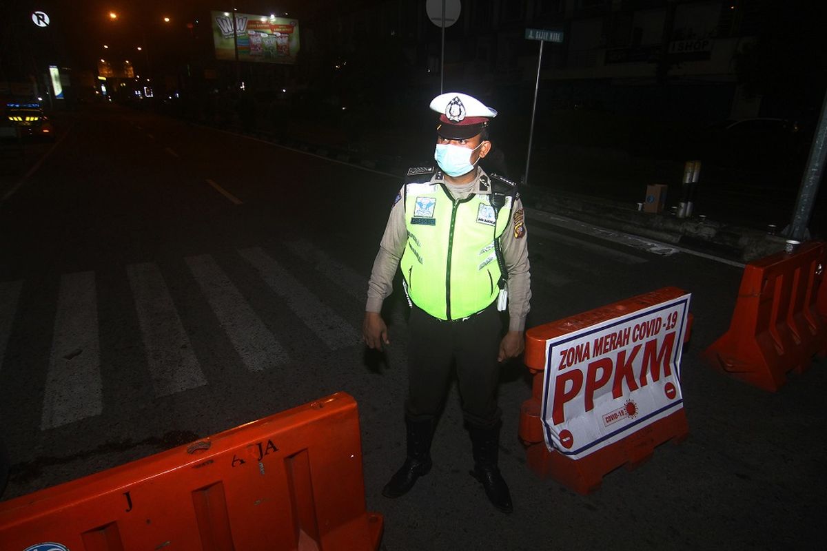 Seorang petugas kepolisian melaksanakan operasi penyekatan PPKM skala Mikro di kawasan pusat perdagangan di Jalan Gajahmada, Pontianak, Kalimantan Barat, Selasa (6/7/2021) malam. Pemerintah daerah setempat bersama kepolisian menutup sejumlah kawasan serta membatasi waktu operasional kegiatan usaha yaitu pukul 14.00 - 17.00 WIB dan 19.00 - 23.00 WIB guna mencegah kerumunan masyarakat karena Pontianak masuk dalam zona merah penyebaran COVID-19. ANTARA FOTO/Jessica Helena Wuysang/wsj.