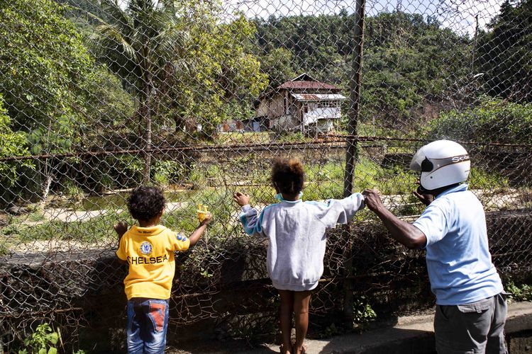 Dua orang anak kecil didampingi orang tuanya sedang melihat buaya di kolam penangkaran di sekitar landing pralayang PON XX Papua 2021, kawasan Entrop Jayapura, Sabtu (25/9/2021) siang. 