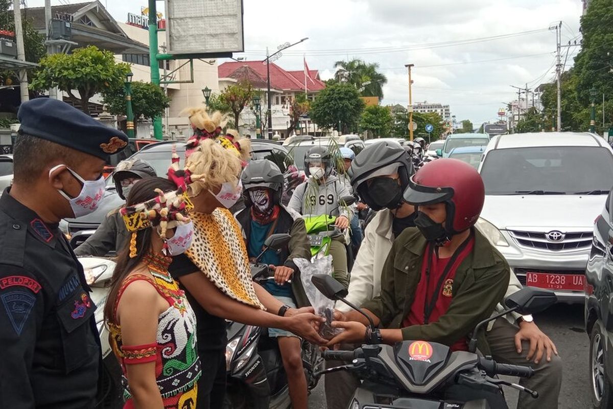 Aliansi Mahasiswa Nusantara dengan pakaian daerah membagikan bibit pohon ke warga yang melintasi kawasan Tugu Pal Putih, Kota Yogyakarta Minggu (28/11/2021)