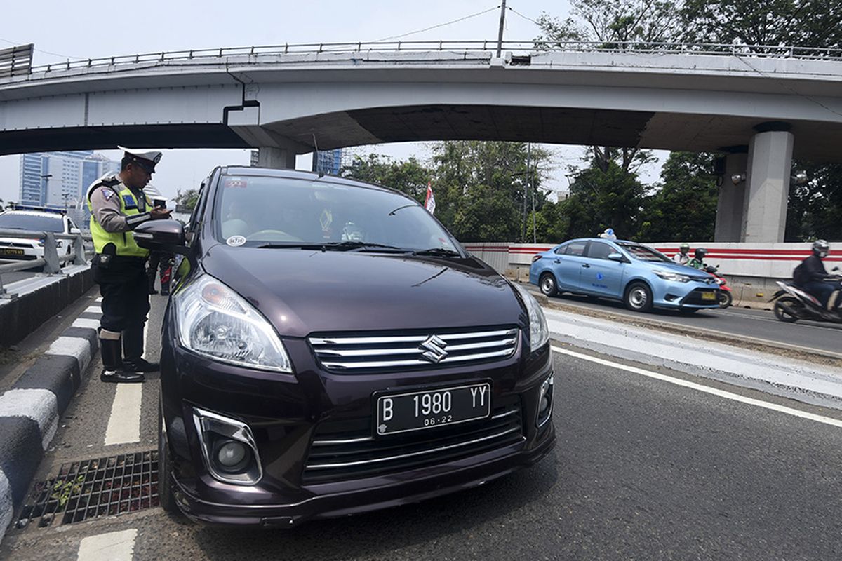 Petugas Ditlantas Polda Metro Jaya memberhentikan mobil berpelat nomor genap yang memasuki Jalan Gatot Soebroto, Jakarta, Rabu (1/8/2018). Petugas kepolisian mulai memberlakukan penindakan berupa tilang terhadap pengendara mobil yang melanggar di kawasan perluasan sistem ganjil-genap.