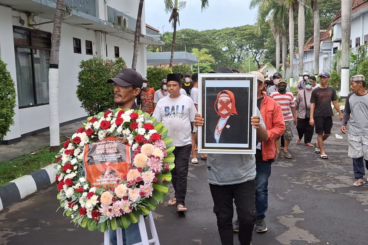 Massa bawa karangan bunga dan foto Ketua DPRD Lumajang Oktafiani dengan tanda silang di wajah ke  Kantor DPRD Lumajang, Jumat (22/11/2024)