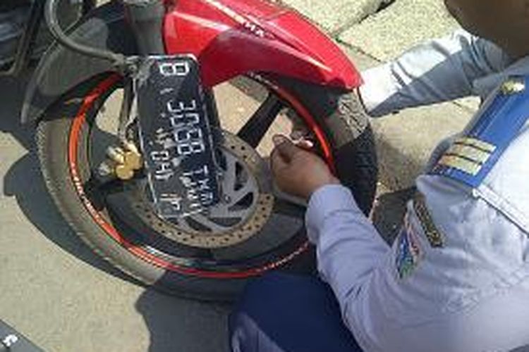 Petugas Sudinhub Jakarta Timur mencabut pentil motor yang parkir di bahu jalan di depan Stasiun Jatinegara, Jakarta Timur, Senin (23/9/2013). Hal tersebut dilakukan untuk mengurangi kemacetan yang sering terjadi di kawasan Jatinegara.