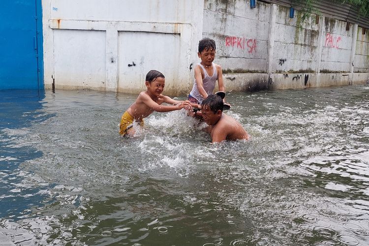 Sejumlah anak-anak memili bermain di genangan banjir di Jalan Mayar Raya, Tegal Alur, Kalideres, Jakarta Barat, Kamis (20/1/2022) siang.