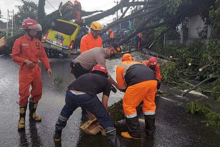 BPBD, Polisi, TNI dan warga sekitar Kota Tasikmalaya sedang mengevakuasi korban dalam mobilnya yang tertimpa pohon tumbang di Jalan Ibrahim Adjie Indihiang, Kota Tasikmalaya, Minggu (9/1/2022).
