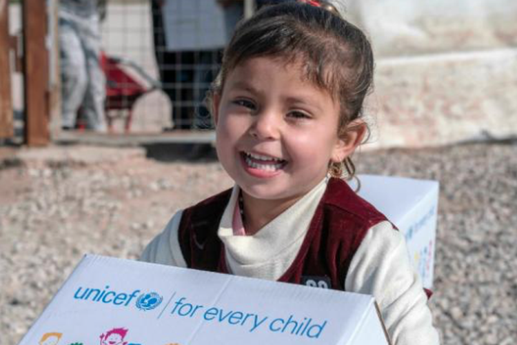 Seorang anak menerima baju bantuan UNICEF.