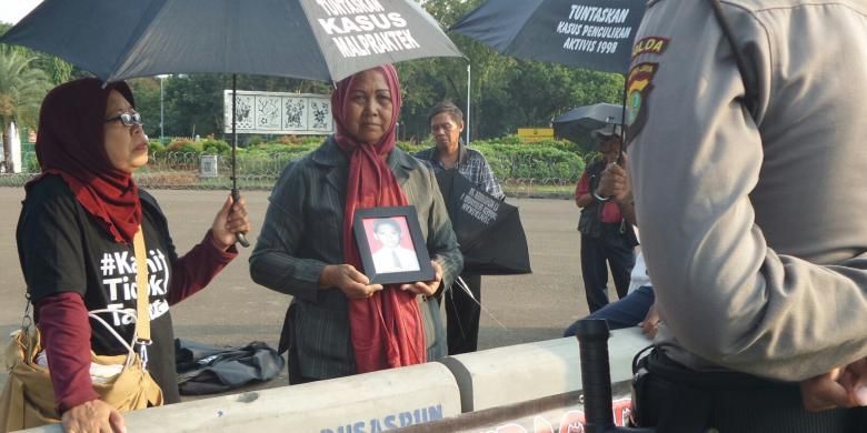Maria Sanu, ibu korban kerusuhan Mei 1998, sedang berdiri sambil memegang foto anaknya yang menjadi korban kerusuhan, dalam Aksi Kamisan ke 443 di depan Istana Negara, Kamis (19/5/2016).