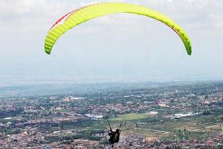 Wisatawan melayang-layang menggunakan paralayang untuk menikmati pemandangan Kota Batu, Jawa Timur, dan pegunungan di sekitarnya, beberapa waktu lalu. Untuk bisa mengudara, pengguna paralayang memulai dari titik tolak di Gunung Banyak di perbatasan Kabupaten Malang dan Batu.