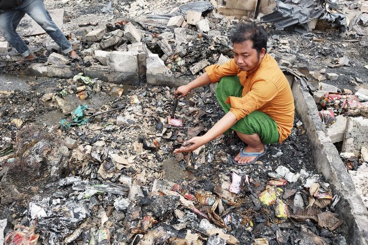 Seorang warga yang terimbas kebakaran di Petojo Selatan, Ahmad Fadil, sedang mengais puing yang tersisa, Senin (27/2/2023). (KOMPAS.com/XENA OLIVIA)