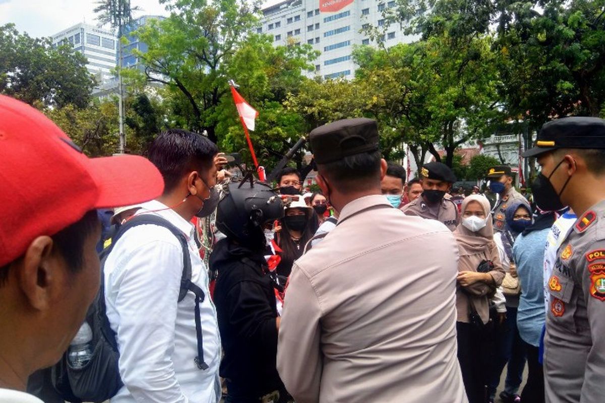 Seorang pria diperiksa polisi karena mengenakan helm dengan aksesoris perkakas di kawasan Jalan Medan Merdeka Utara, Jakarta Pusat, Rabu (17/8/2022).