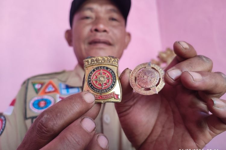 Sisdohiri menunjukkan lencana Tagana Muda dan Tagana Madya yang dia dapat usai penanganan bencana di berbagai daerah, sejak tahun 2010 hingga 2024, di rumahnya, di Desa Cipinang, Kecamatan Beber, Kabupaten Cirebon, Jawa Barat, Senin (6/5/2024) siang.