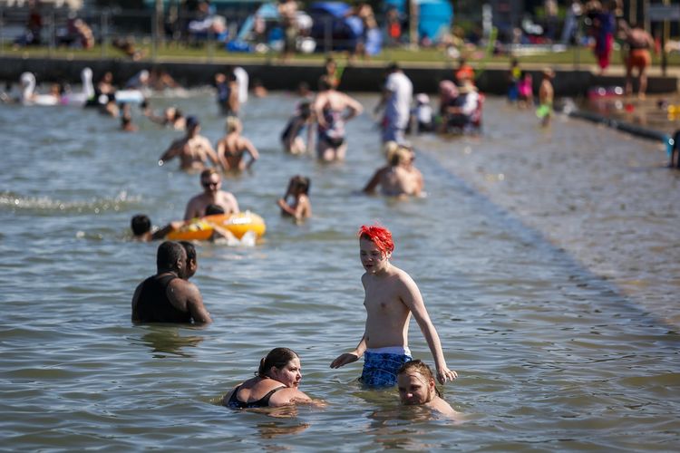 Orang-orang mencoba mengalahkan panas dengan berendam di pantai Chestermere, Alta, pada Selasa, 29 Juni 2021. Badan cuaca Kanada memprediksi gelombang panas bakal menghantam dengan mulai ada kabar suhu yang semakin tinggi.