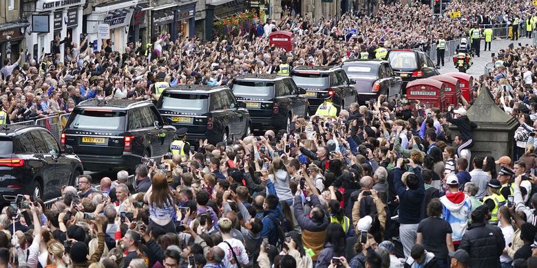 Crowds watch as the hearse carrying the coffin of Queen Elizabeth II, draped with the Royal Standard of Scotland, passes Mercat Cross in Edinburgh, Sunday, Sept. 11, 2022, as it continues its journey to the Palace of Holyroodhouse from Balmoral. 