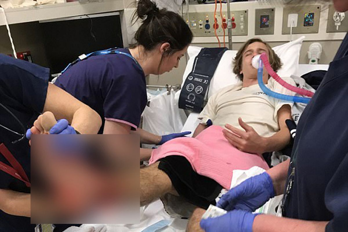 Sam Kanizay, ditangani tim medis saat mengalami pendarahan di kaki setelah keluar dari air, usai berenang di pantai Brighton, di pinggiran Kota Melbourne, Sabtu malam lalu. Darang mengalir tak henti dari pergelangan kaki dan betis remaja itu.  