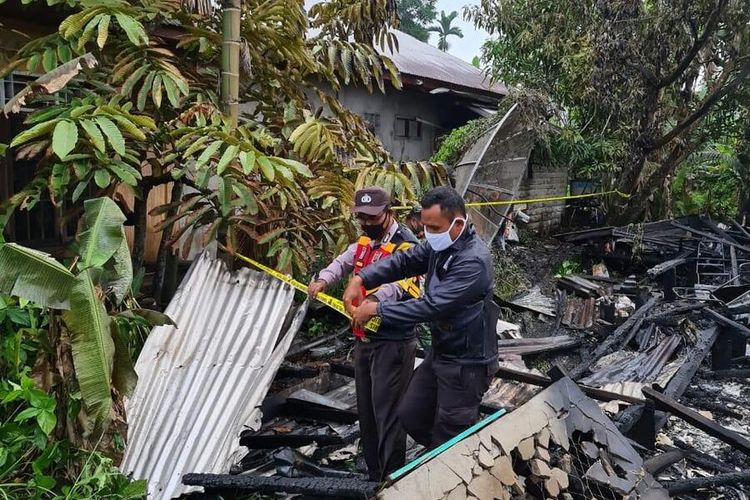 Petugas kepolisian memasang garis polisi untuk dilakukan penyelidikan pada kasus kebakaran rumah yang menewaskan satu keluarga di Jalan M Chalid, Desa Teluk Pantaian, Kecamatan Gaung Anak Serka, Kabupaten Inhil, Riau, Senin (24/8/2020) dini hari.