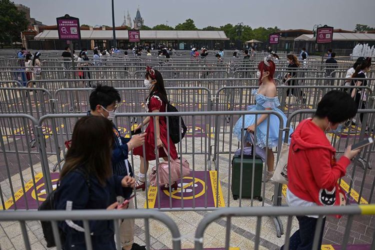 Pengunjung mengenakan masker, mengantre dengan aturan pembatasan jarak (physical distancing) saat hendak masuk ke taman hiburan Disneyland, Shanghai, China, yang baru dibuka kembali, Senin (11/5/2020). Shanghai Disneyland resmi kembali dibuka setelah ditutup selama 4 bulan akibat pandemi virus corona.