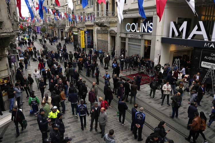 Orang-orang berkumpul di sekitar tugu peringatan yang ditempatkan di lokasi ledakan hari Minggu di Istiklal Avenue pejalan kaki Istanbul yang populer di Istanbul, Senin, 14 November 2022. 