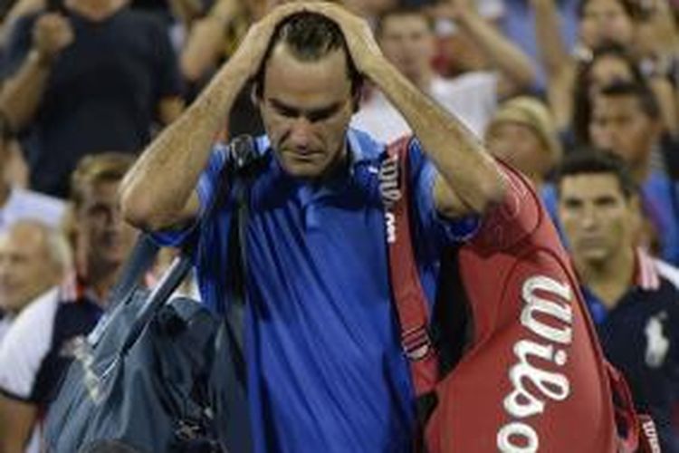 Petenis Swiss, Roger Federer menyeka rambutnya, tertunduk, saat meninggalkan lapangan usai dikalahkan Tommy Robredo pada babak keempat US Open, Senin (2/9/2013).