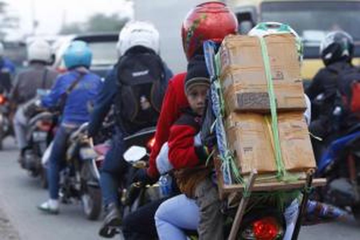 Pemudik bersepeda motor membawa anaknya, saat melintasi ruas Jalan Kalimalang, Bekasi, Jawa Barat, Selasa (14/7/2015). Arus pemudik bersepeda motor diperkirakan akan melonjak mulai malam ini hingga satu hari sebelum Lebaran Idul Fitri 1436 H.