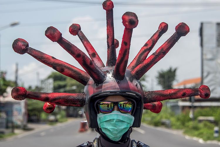 Anggota polisi memakai helm berbentuk virus corona melakukan imbauan dan penyemprotan cairan disinfektan pada kendaraan di jalanan di daerah Mojokerto, Jawa Timur, Jumat (3/4/2020). Cara unik ini dilakukan oleh sejumlah anggota dari Polres Mojokerto dalam upaya menekan penyebaran virus corona atau penyakit Covid-19 yang tengah merebak di Tanah Air.