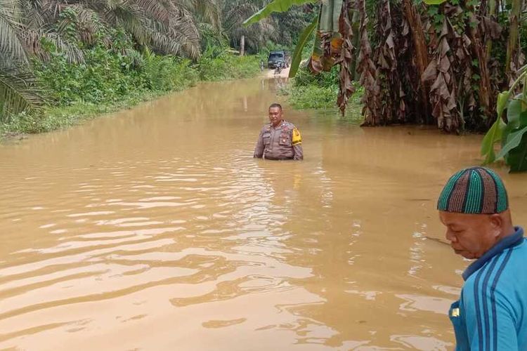 Bhabinkamtibmas Desa Siambul, Bripka Habibi memantau kondisi banjir yang merendam jalan poros penghubung dua desa di Kecamatan Batang Gansal, Kabupaten Inhu, Riau, Sabtu (5/11/2022).