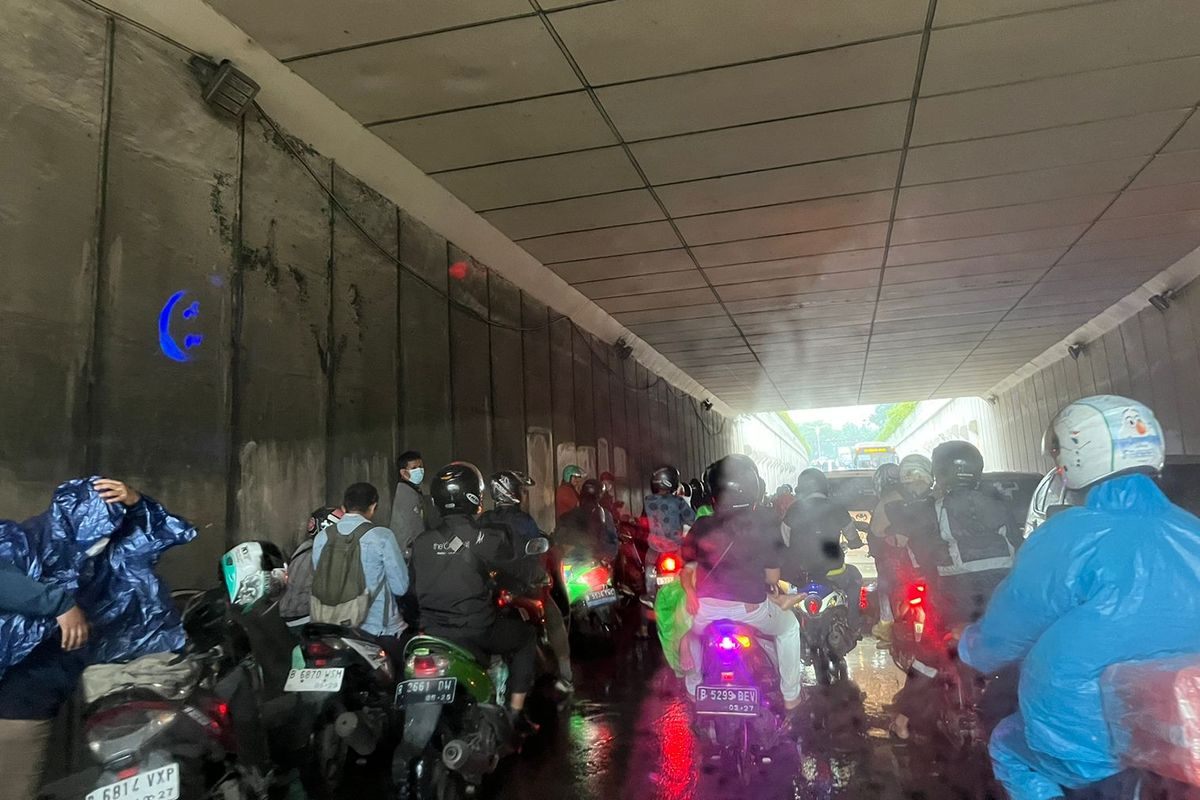 Beberapa pengendara motor berteduh di underpass dekat Gandaria City, Kebayoran Lama, Jakarta Selatan, Jumat (8/12/2023). Hal ini menyebabkan jalanan macet parah.