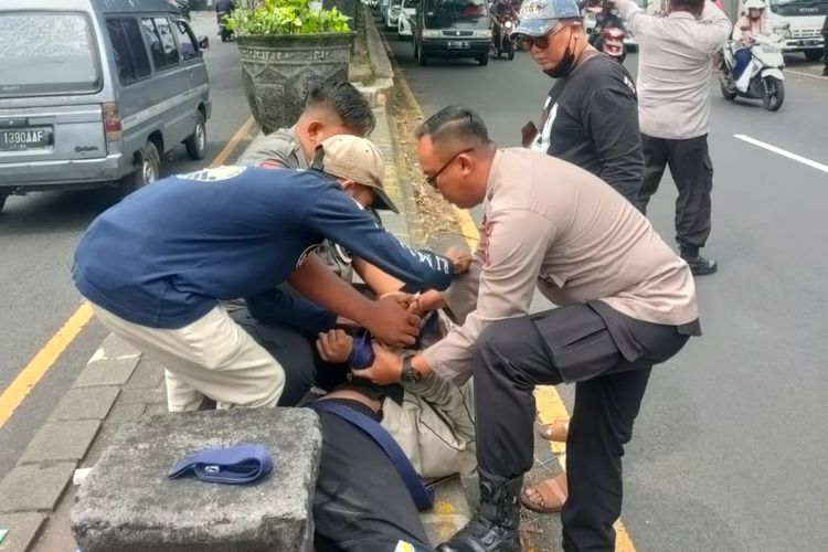 Petugas Polsek Singosari saat melakukan pengamanan kepada seorang ODGJ, Indrianto di pinggir jalan utama Malang-Surabaya, Rabu (9/11/2022).