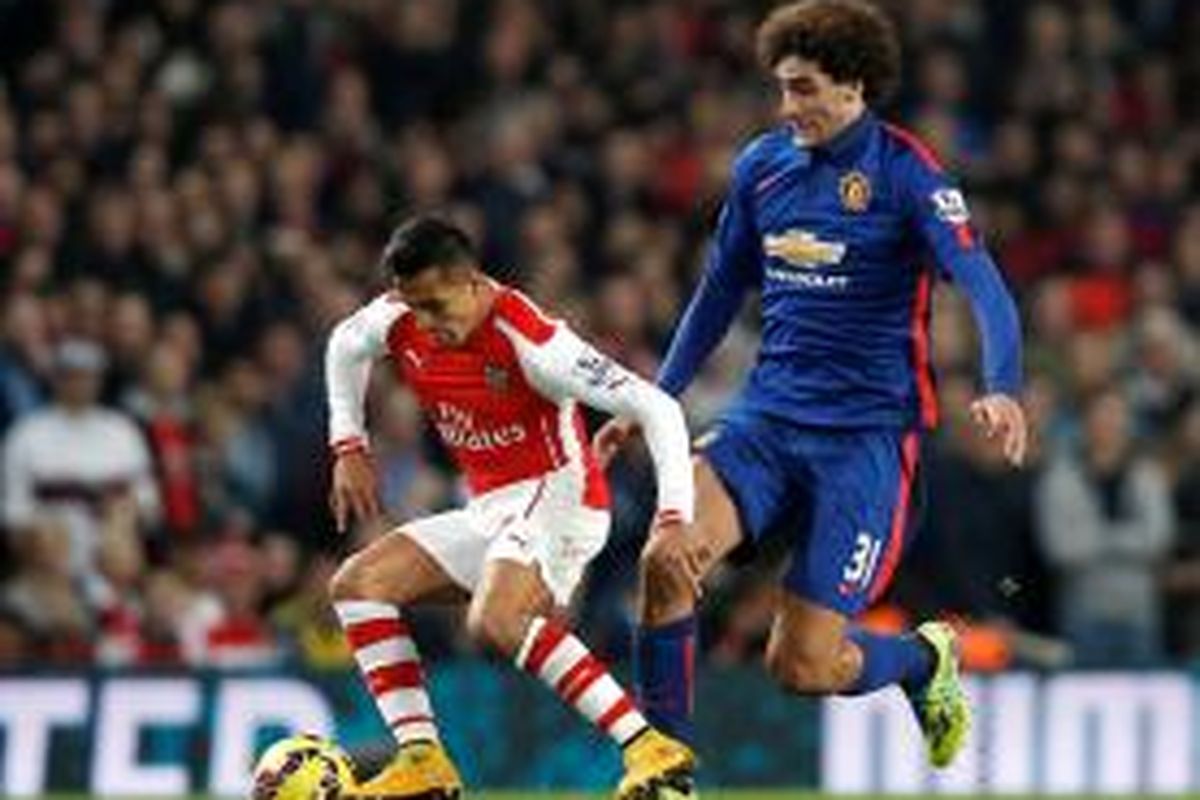 Striker Arsenal, Alexis Sanchez, saat mengamankan bola dari hadangan gelandang Manchester United, Marouane Fellaini, pada lanjutan Premier League di Emirates, Sabtu (22/11/2014). 