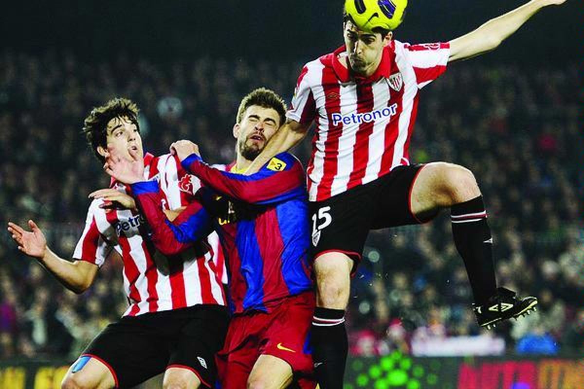 Bek Barcelona, Gerard Pique (tengah), berusaha mengatasi serbuan pemain Athletic Bilbao, Andoni Iraola (kanan), dalam laga Piala Raja di Stadion Nou Camp, Barcelona, Spanyol, Selasa (21/12). Athletic Bilbao menahan seri Barcelona, 0-0.