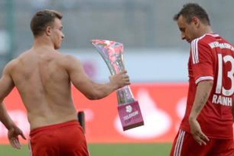 Gelandang Bayern Muenchen, Xherdan Shaqiri, menunjukkan trofi Telekom Cup kepada rekannya, Rafinha. Bayern memenangkan trofi ini setelah mengalahkan Borussia Moenchengladbach 5-1 pada partai final, Minggu atau Senin (22/7/2013) dini hari WIB.