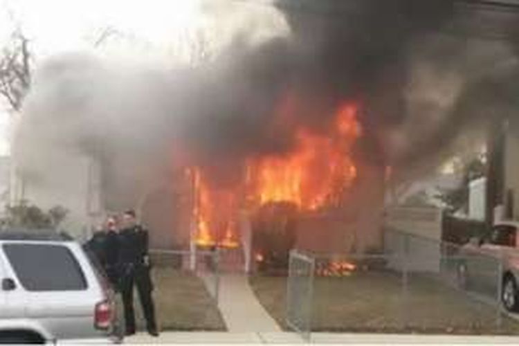 Dua orang polisi yang tertangkap kamera menjepret selfie di depan rumah yang terbakar di daerah Long Island, Amerika Serikat.