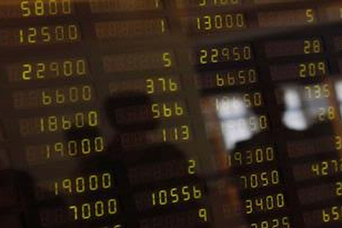 Refleksi pengunjung di papan indeks harga saham gabungan (IHSG) di Mandiri Sekuritas, Jakarta, Jumat (13/4/2012). 